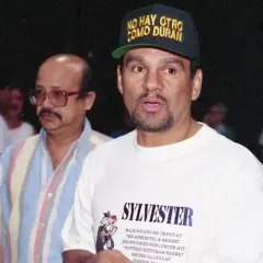 Roberto Duran reach, wearing a cap that says "No Hay Otro Como Duran." He's in a white t-shirt with "Sylvester" printed on it.