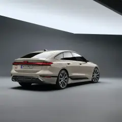 Elegancki tył nowego Audi A6 2025 w kolorze piaskowym, z charakterystycznym pasem świateł LED i sportowymi felgami.