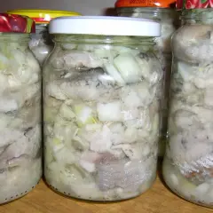 Słoiki z najsmaczniejszymi śledziami w oleju, przygotowanymi z cebulką. Domowy przysmak gotowy do spożycia.