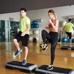 Para ćwiczy ćwiczenia na stepie w siłowni.