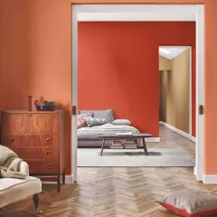 Un soggiorno accogliente con pareti arancioni, un divano letto e un mobile vintage. Perfetto per chi vuole imbiancare casa con stile.
