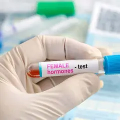 Rękawiczka medyczna trzyma probówkę z krwią do badania poziomu hormonów, w tym FSH.
