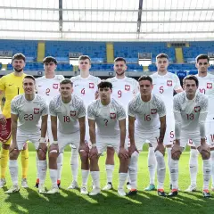 Młodzieżowa reprezentacja Polski w piłce nożnej pozuje do zdjęcia na stadionie.