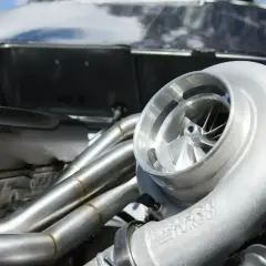 Błyszcząca turbosprężarka w silniku p0299 vw. Metalowe kolektory wydechowe i błyszcząca obudowa silnika.