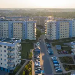 Widok z lotu ptaka na osiedle bloków mieszkalnych z balkonami i parkingami.