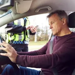 Mann am Steuer, Polizist mit Handy. Die Konsequenzen von Alkohol am Steuer sind eine empfindliche Strafe.