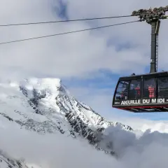 La télécabine de l'Aiguille du Midi survole un paysage alpin spectaculaire, transportant des passagers vers les sommets enneigés.
