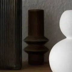 Drei Vasen in verschiedenen Formen und Farben: eine hohe, geriffelte dunkle, eine braune mit zwei Wölbungen und eine weiße, kugelförmige. Perfekt zum Vase dekorieren ohne Blumen.