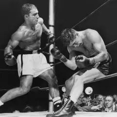 Two boxers in a ring, one on the offensive. Rocky Marciano, who won all 49 of his professional fights, is depicted here.