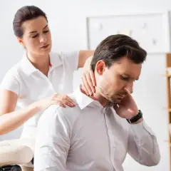 Une thérapeute prodigue un massage au bureau à un homme d'affaires, soulageant ses tensions au cou et aux épaules.