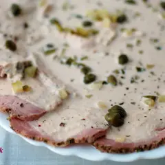 Cienkie plastry pieczonego mięsa wieprzowego polane kremowym sosem z kaparami i ziołami, klasyczne vitello tonnato.