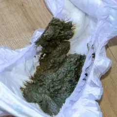 Zielona kupa w pieluszce, która wymaga zmiany.