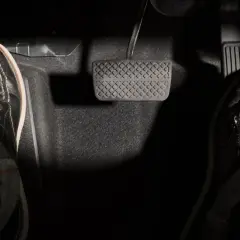 Dwie stopy w czarnych butach na pedałach samochodu.