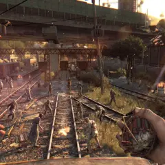 Gracz trzyma granat, otoczony przez hordę zombie na torach kolejowych. To scena z gry Dying Light, gdzie wymagania sprzętowe są kluczowe dla płynności rozgrywki.