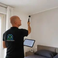 Tecnico con fonometro e tablet esegue una misurazione per la correzione acustica in una stanza da letto.