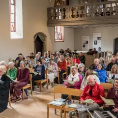 Menschen sitzen in einer Kirche und singen. Dies ist ein Beispiel dafür, was ist eine Freikirche: eine Gemeinschaft, die sich selbst organisiert.