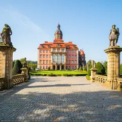 Zamek Książ z różową fasadą i wieżą, otoczony ogrodem. Poznaj zamek Książ ciekawostki i jego tajemnice.