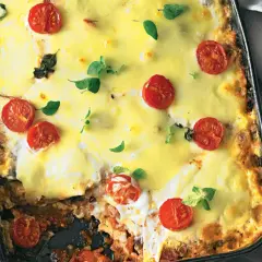 Herzhafte low carb Lasagne mit geschmolzenem Käse und Kirschtomaten, garniert mit frischen Kräutern.