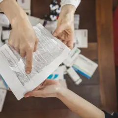 Mani che consultano un foglietto illustrativo tra scatole di medicinali, spiegando il significato di "off label" per un uso non previsto.