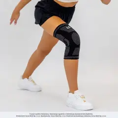 Czarny stabilizator na udo z szarymi wzorami, noszony przez kobietę podczas ćwiczeń.