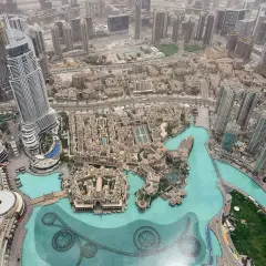 Widok z góry na Dubaj, z najwyższym budynkiem w Dubaju, Emaar, dominującym nad miastem i otoczonym przez turkusową wodę.