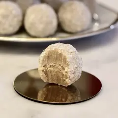 En bit tagen ur en av de fluffiga vita chokladbollarna, som är rullade i kokosflingor.