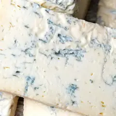 Fette di formaggio verde, con venature blu intenso, che ricordano il sapore deciso del gorgonzola.