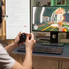 Gracz z kontrolerem w rękach gra w grę na komputerze, szukając inspiracji na nazwy do Fortnite w czacie.