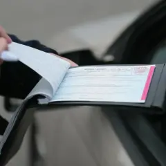 Policjant spisuje mandat karny po stłuczce. Dokument zawiera numer 1934776.