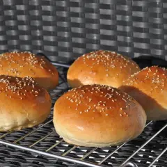 Fünf goldbraune Burgerbrötchen mit Sesam, frisch gebacken nach einem tollen burger buns rezept.