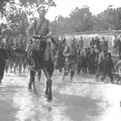 Żołnierze w historycznych mundurach, w tym na koniu, maszerują w zwartym szyku. To widok nawiązujący do czasów, gdy formowały się legiony polskie.