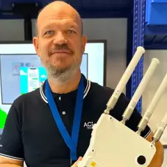 Un homme souriant tient un appareil avec quatre antennes, prêt à optimiser votre reseau wifi.