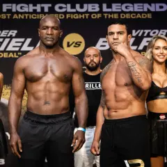 Evander Holyfield och Vitor Belfort står redo för en episk match. Ringflickor flankerar de muskulösa boxarna.