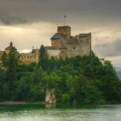 Zamek w Niedzicy, niczym zamek Janosika, góruje nad jeziorem, otoczony bujną zielenią.