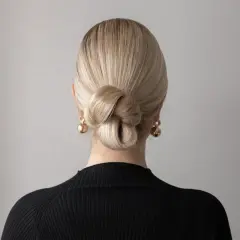 Elegancki kok z blond włosów, idealny na proste fryzury ślubne. Złote kolczyki dodają blasku.