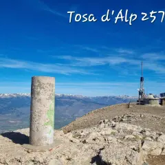 Cima de Tosa d'Alp, 2578m. Pilar de hormigón y antena de telecomunicaciones en un día soleado con vistas a montañas nevadas.