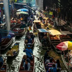 Livligt marknadsliv i Bangkok med båtar fyllda med varor och människor som navigerar på kanalen.