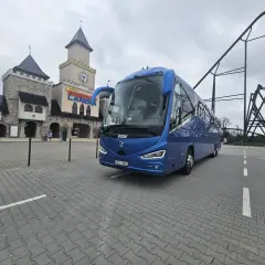 Niebieski autokar przed zamkiem w Energylandii, gotowy na wycieczkę z Wrocławia.