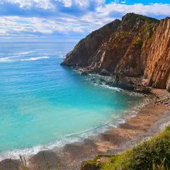 Aguas turquesas bañan la **cascada playa del Silencio**, rodeada de imponentes acantilados ocres y vegetación exuberante.