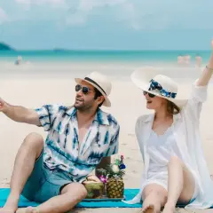 Para na plaży robi selfie z kamerką GoPro, ciesząc się wakacjami. W tle błękitne morze i niebo.