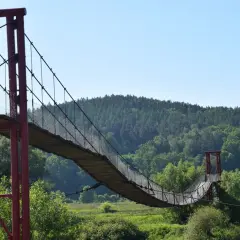 Drewniany most wiszący, najdłuższy w Polsce, wije się nad zieloną doliną.