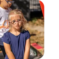 Dziewczynka z zespołem Downa w okularach patrzy w obiektyw. Obok stoi chłopiec.