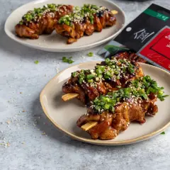Pyszne yakitori na patyczkach, polane sosem i posypane sezamem i szczypiorkiem. Obok opakowanie sosu Yakitori.