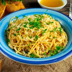 Aglio olio z parmezanem i natką pietruszki, podane z grzankami czosnkowymi.