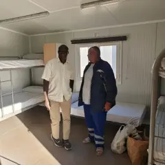 Dos hombres observan literas en un alojamiento temporal, un ejemplo de trabajo a cambio de alojamiento.