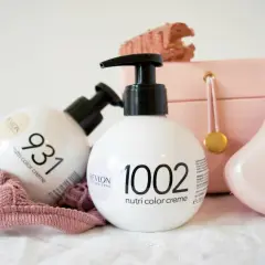 Två flaskor Revlon hårfärg, Nutri Color Creme, står framför en rosa smyckeskrin och en rosa tygbit.
