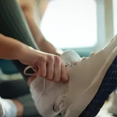 Dłoń zawiązuje sznurówki w białych butach sportowych. Może to być znak, że nawet za duże buty mogą być wygodne do biegania.
