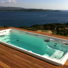 Biała wanna spa z hydromasażem na drewnianym tarasie z widokiem na morze.