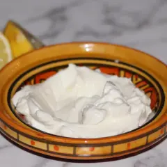 Krämig vitlökssås, perfekt för ditt toum recept. Citron och vitlök bredvid skålen.