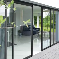 Une baie vitrée coulissante moderne avec un salon visible à travers. Pensez à lubrifier le rail pour une ouverture fluide.